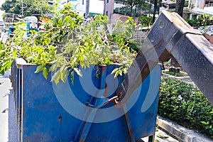 Close-up garbage container latch with truck full of garden refuse