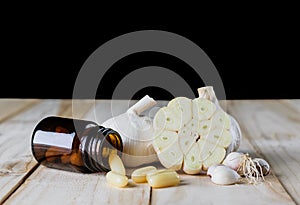 Close up garlic and oil capsule gel supplement on wood white background