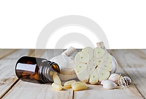 Close up garlic and oil capsule gel supplement on wood white background