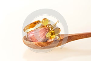 Close up garlic and oil capsule gel supplement in a wooden spoon