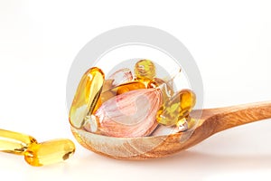 Close up garlic and oil capsule gel supplement in a wooden spoon