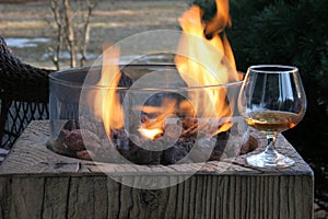 Close-up of gas fire pit with a snifter of cognac