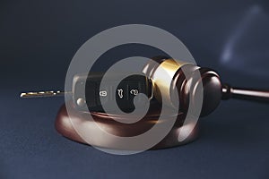 Close-up Of Gavel And Car Key On Sounding Block Against Grey Background