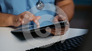 Close up of general practitioner nurse holding tablet computer typing medical expertise