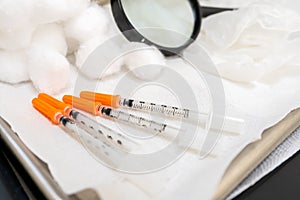 Close up of generic needle syringes with orange caps, for diabetes insulin injections, or medical injection formulas in a doctor