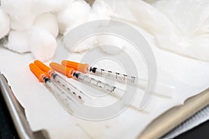 Close up of generic needle syringes with orange caps, for diabetes insulin injections, or medical injection formulas in a doctor