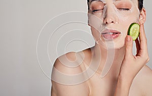 Close up gentle sophisticated calm girl in a moisturizing mask with a fresh cucumber