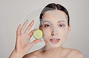 Close up gentle sophisticated calm girl in a moisturizing mask with a fresh cucumber on the face