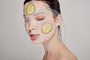 Close up gentle sophisticated girl in a moisturizing mask with a fresh cucumber on the face
