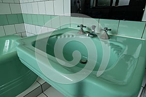 Close up of original green vintage retro 1930s deco wash basin and stainless steel taps.