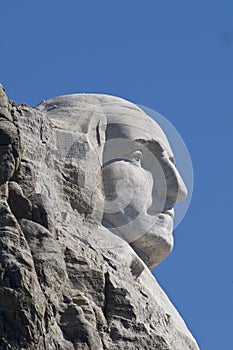 Close up of George Washington`s head on Mount Rushmore with solid blue sky