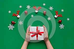 Close up gif box on hands on green background. Kids holding white gift box. Christmas, New year.