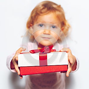 Close-up of gift box with red ribbon bow in children girl hands