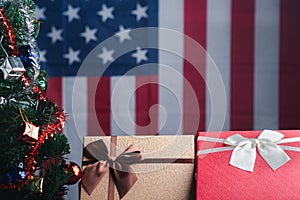 Close-up of gift boxes and a Christmas tree with an American flag in the background. Space for text. Concept of Christmas and new