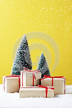 Gift boxes, Christmas tree on table and yellow background.