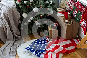 Close-up of gift boxes and a Christmas tree with an American flag in the background. Space for text. Concept of