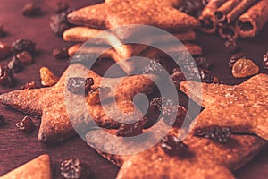 Close up of ginger cookies in the shape of a star with raisins on a red wood