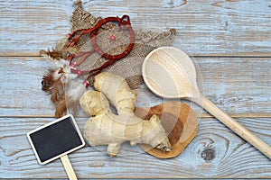 Close up of ginger root on old wooden planks background with wooden spoon and blackboard tag with empty copy space