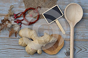 Close up of ginger root on old wooden planks background with wooden spoon and blackboard tag with empty copy space