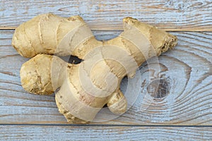 Close up of ginger root on old wooden planks background with wooden spoon and blackboard tag with empty copy space