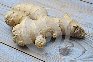 Close up of ginger root on old wooden planks background with wooden spoon and blackboard tag with empty copy space