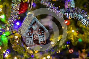 Close up of gingerbread toy houses a christms tree decoration hanging on a fir branch