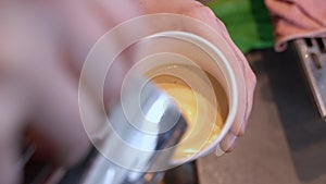 Close-up of a girl drawing latte art on coffee in a red cup in a coffee shop. drawing on a cup of coffee.