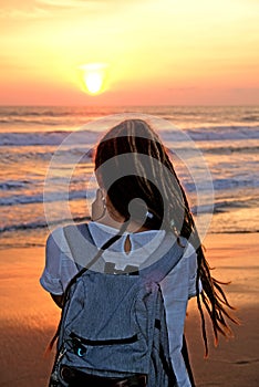 A close up of a girl with dreadlocks looking at the beautiful ocean sunset