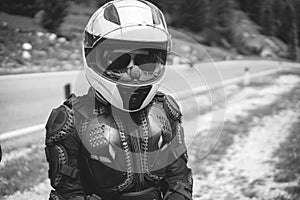 Close up of girl dressed in protective suit of body armor, tutle prtotective jacket, with helmet and glowes. Mountains road on