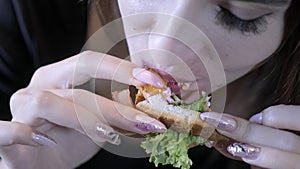 Close-up. girl eats fast food. Eats a sandwich. Concept of healthy eating and obesity society