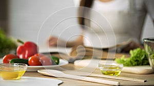 Close-up of girl flipping through cooking book pages, choosing salad recipe