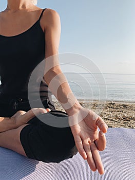 Close up girl hands in mudra meditation posture on sea shore at sunrise