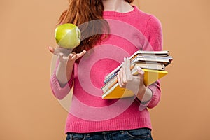 Close up of a girl holding apple and books