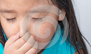 Close up of a girl holding her nose because of a bad smell.