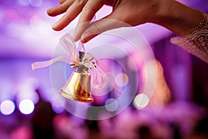 Girl holds in hand a Christmas bell on lights background