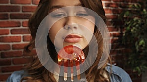 Close up of a girl looking at a fork with half of a ripe red cherry tomato. Creative food advertising concept. POV.
