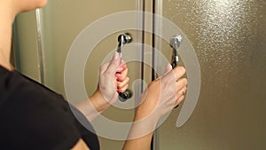 Close-up girl opens the glass door in shower cabin