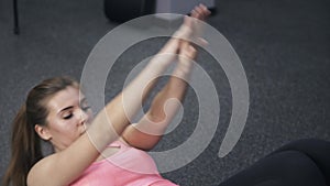 Close up of girl in pink doing situps in a gym