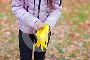 Close-up of a girl in a pink jacket dresses yellow gloves.