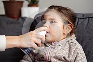 Close up of girl portrait with nose spay treatment of adenoids.