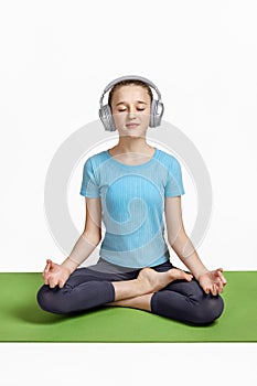 Close-up of a girl practicing yoga meditation exercises, a teenager sitting on a mat.