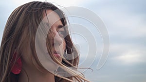 Close-up of the girl's face, the camera moves around the blonde. Wind hair