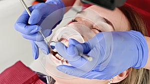 A close-up of the girl`s face is examined by a dental examiner with his mouth open and a napkin and eyes closed. Dentist
