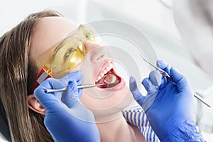 A close-up of the girl`s face is examined by a dental examiner with his mouth open and a napkin and eyes closed. Dentist