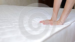 Close up of a girl's hand checks the rigidity of a new comfortable orthopedic white mattress for the bed. Female