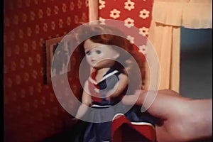 Close-up of girl's hand playing with doll in dollhouse