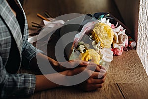 Close-up of a girl`s hands in a cafe with a bouquet lying next to it.Beckett is lying on the counter in the cafe and next to the