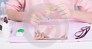Close up, girl`s hands hold a container for storing contact lenses, to improve vision