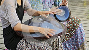 Close-up of girl's hands playing tank drum or hang on ethnic open air concert