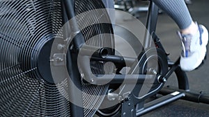 Close-up of a girl's legs pedaling while exercising on a bicycle in the gym. Cardio training